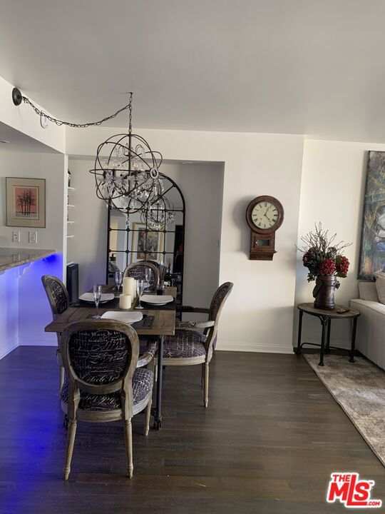 dining room with dark wood-type flooring and a chandelier