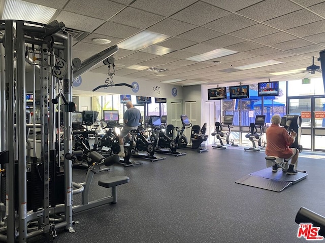 gym featuring a wall of windows and a drop ceiling