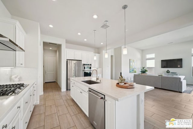 kitchen featuring a center island with sink, appliances with stainless steel finishes, pendant lighting, white cabinets, and sink