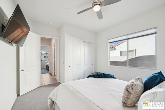 carpeted bedroom with ceiling fan and a closet