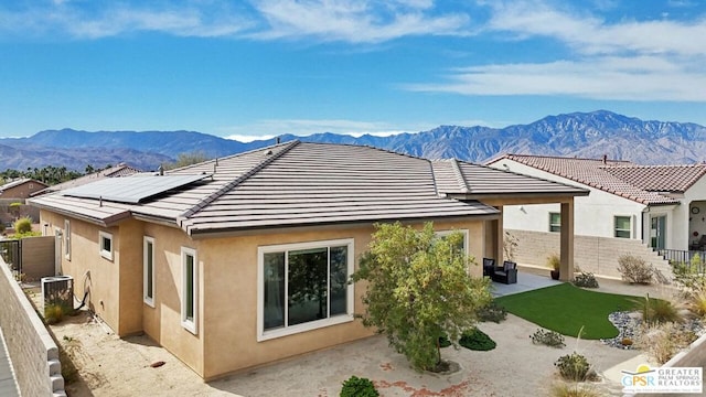 back of house with central air condition unit, a mountain view, solar panels, and a patio