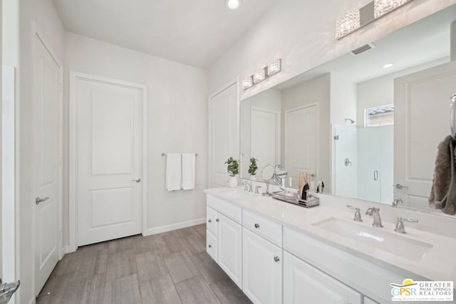 bathroom featuring a shower with door and vanity