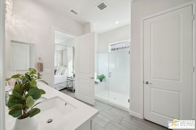 bathroom with a shower with shower door and vanity