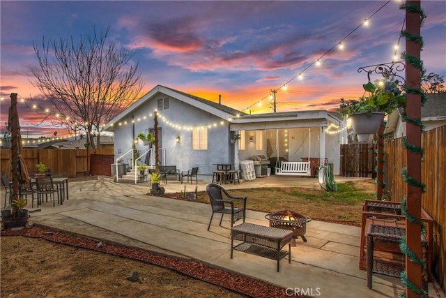 back house at dusk with a patio area and an outdoor fire pit