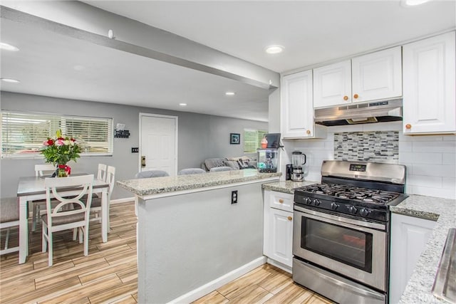 kitchen with kitchen peninsula, white cabinetry, tasteful backsplash, light stone counters, and gas stove