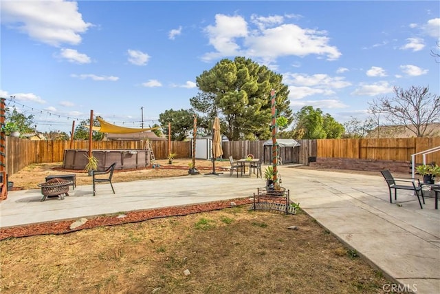 view of yard with a shed, a hot tub, a fire pit, and a patio