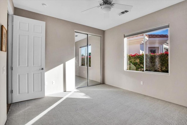 unfurnished bedroom featuring light carpet, ceiling fan, and a closet