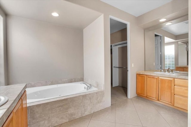 bathroom with vanity, a relaxing tiled tub, and tile patterned floors