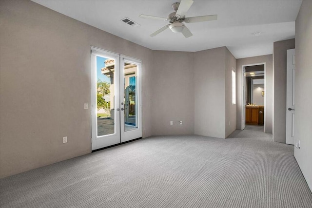 carpeted spare room with ceiling fan and french doors