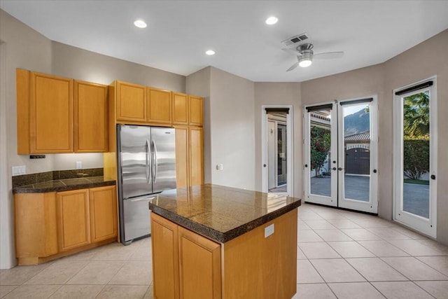 kitchen featuring stainless steel refrigerator, ceiling fan, a kitchen island, light tile patterned flooring, and french doors