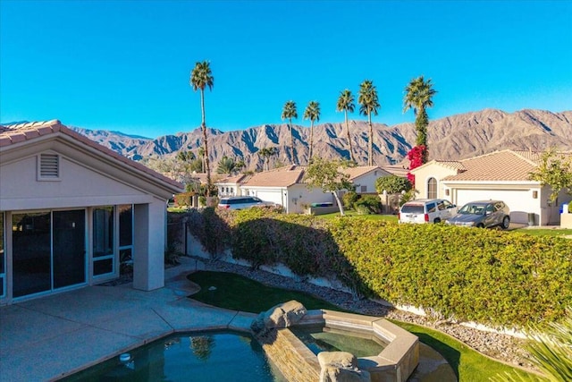 view of pool featuring an in ground hot tub, a mountain view, and a patio area