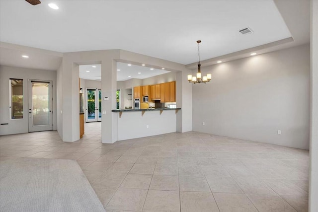 kitchen featuring a kitchen breakfast bar, hanging light fixtures, light tile patterned floors, a notable chandelier, and kitchen peninsula