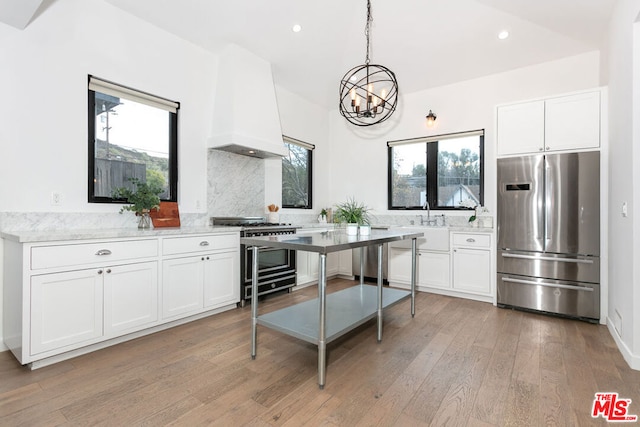 kitchen featuring decorative light fixtures, a notable chandelier, premium range hood, stainless steel appliances, and white cabinets