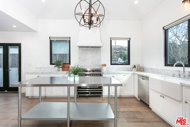 kitchen featuring decorative light fixtures, premium range hood, sink, stainless steel appliances, and white cabinets