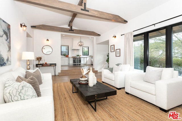 living room featuring lofted ceiling with beams, a notable chandelier, and hardwood / wood-style floors