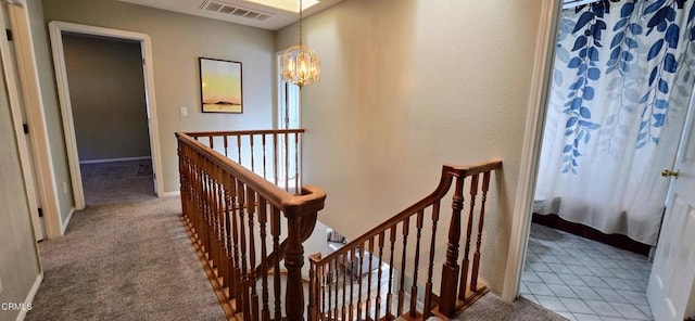 hallway with a chandelier and carpet flooring