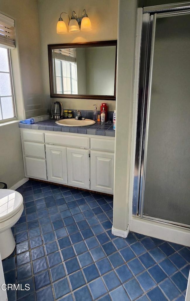 bathroom featuring toilet, a shower with door, tile patterned floors, and vanity