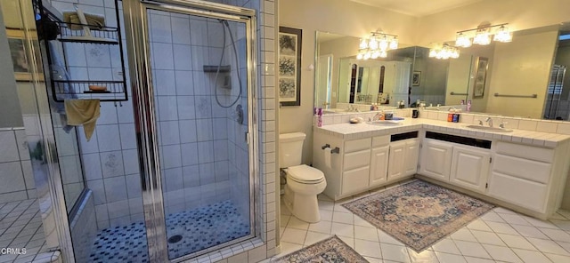 bathroom featuring tile patterned floors, a shower with door, toilet, and vanity