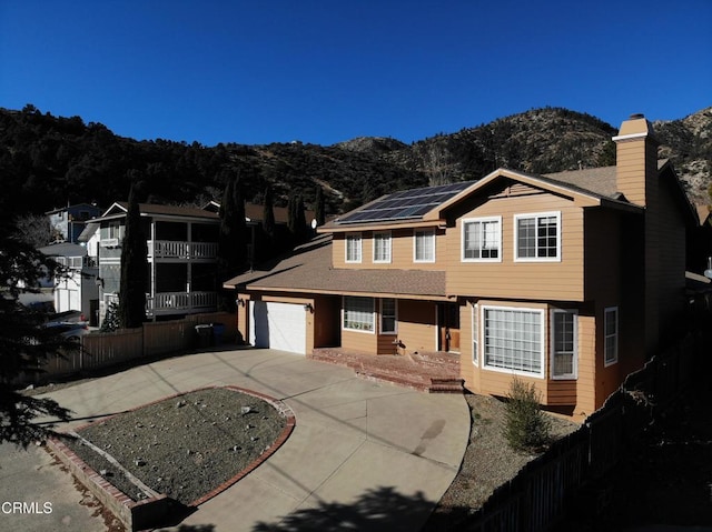 view of front of home featuring a mountain view, solar panels, and a garage