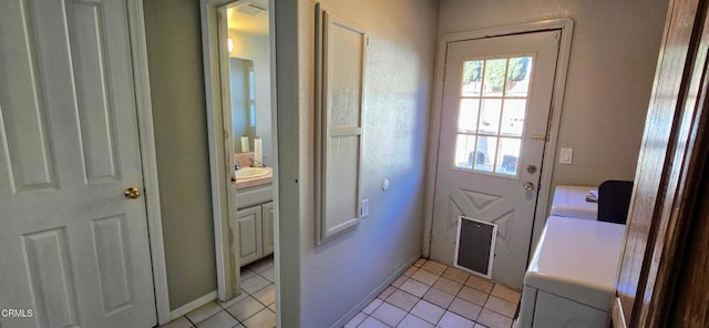 doorway with washer and dryer, sink, and light tile patterned flooring