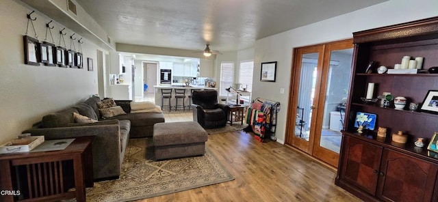 living room featuring ceiling fan, light hardwood / wood-style flooring, and french doors