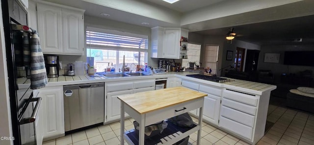 kitchen featuring light tile patterned flooring, stainless steel appliances, tile countertops, and white cabinets