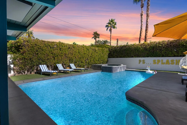 pool at dusk with an in ground hot tub and a patio