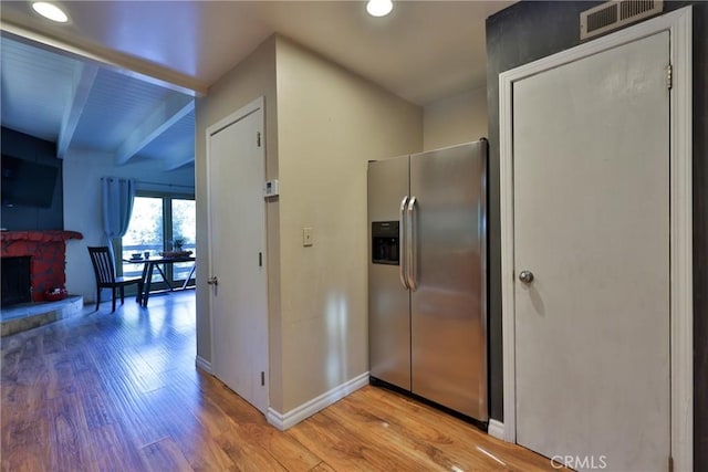 kitchen featuring visible vents, stainless steel fridge, beam ceiling, and light wood-style floors
