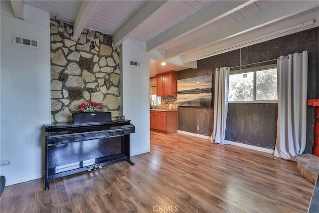 interior space featuring visible vents, wood finished floors, and beamed ceiling