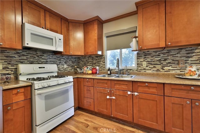 kitchen with tasteful backsplash, white appliances, light wood-style flooring, brown cabinets, and a sink