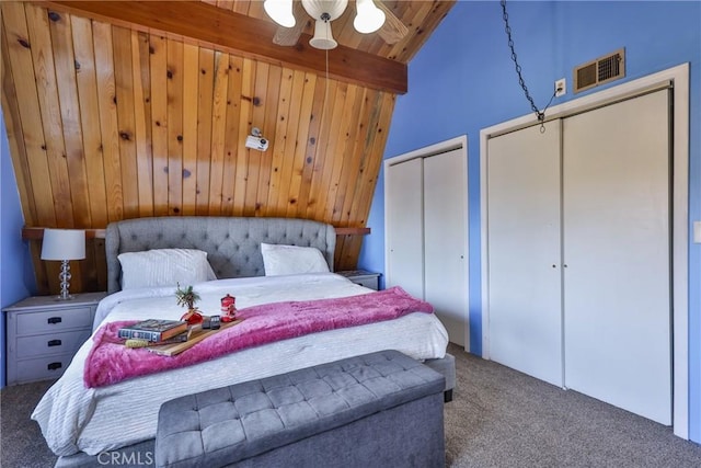 bedroom with visible vents, carpet, wood ceiling, multiple closets, and vaulted ceiling with beams