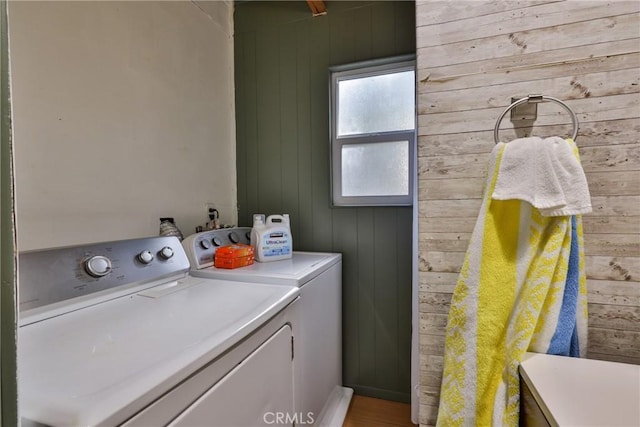 laundry room featuring wooden walls, wood finished floors, separate washer and dryer, and laundry area
