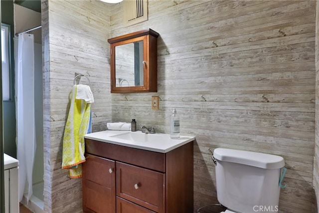 bathroom featuring wood walls, toilet, curtained shower, and vanity