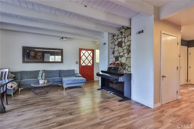 living room featuring visible vents, baseboards, beam ceiling, and wood finished floors