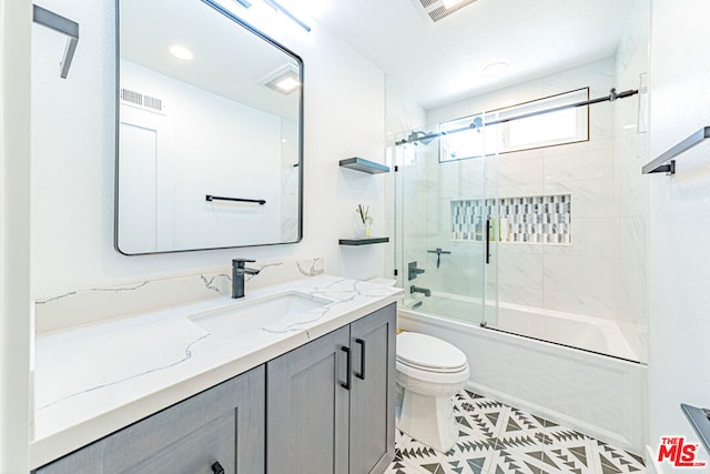 full bathroom with combined bath / shower with glass door, vanity, toilet, and tile patterned flooring