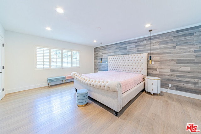 bedroom with light wood-type flooring and wood walls