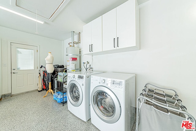 clothes washing area with water heater, cabinets, and washing machine and dryer