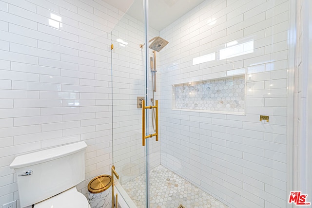 bathroom featuring toilet and a shower with shower door