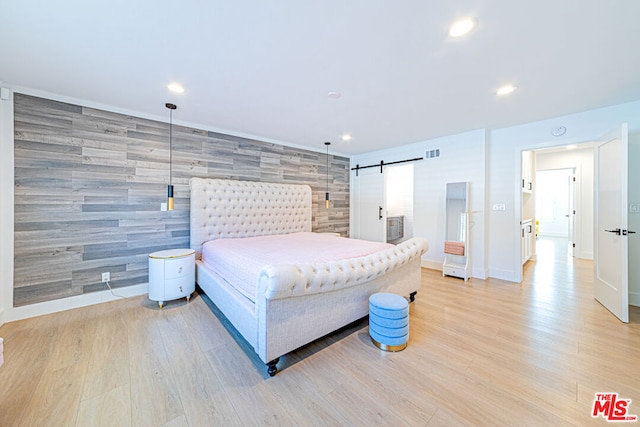 bedroom featuring light wood-type flooring and a barn door