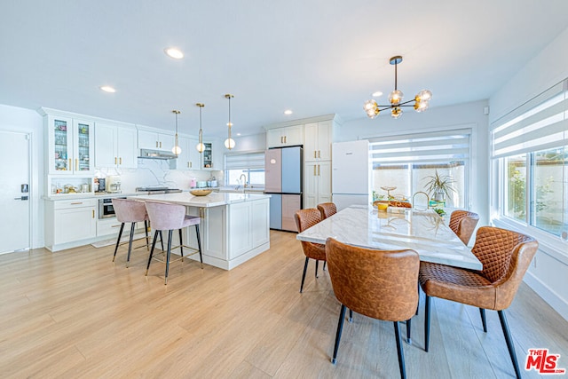 dining space featuring light wood-type flooring, an inviting chandelier, and sink