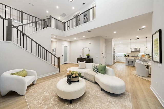 living room with a towering ceiling and light hardwood / wood-style flooring