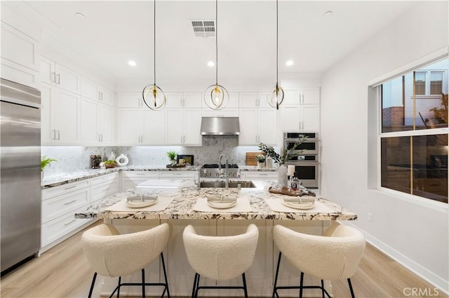 kitchen featuring white cabinets, sink, stainless steel appliances, and pendant lighting