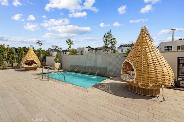 view of swimming pool with pool water feature, a patio, and an outdoor brick fireplace