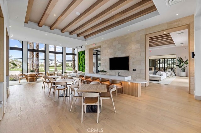 dining room featuring light wood-type flooring, a wall of windows, and a tray ceiling