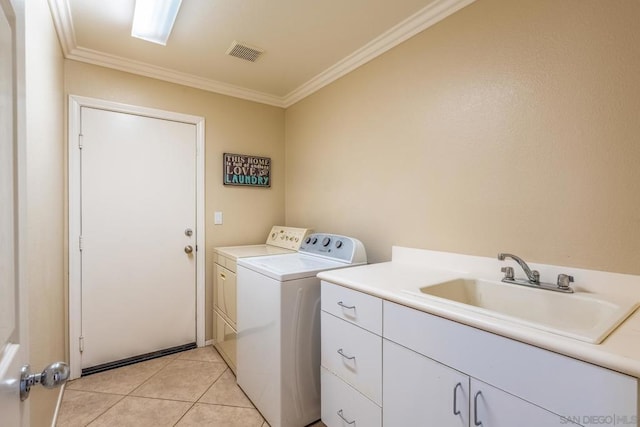 washroom featuring washing machine and dryer, cabinets, sink, ornamental molding, and light tile patterned floors