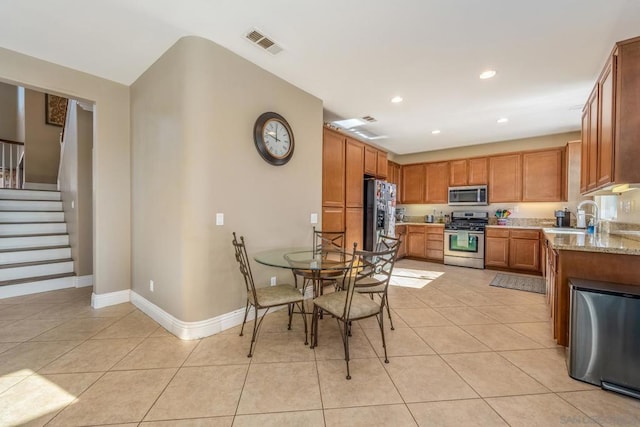 kitchen featuring light stone countertops, light tile patterned floors, appliances with stainless steel finishes, and sink