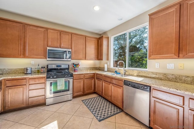 kitchen featuring light tile patterned floors, sink, light stone counters, and stainless steel appliances