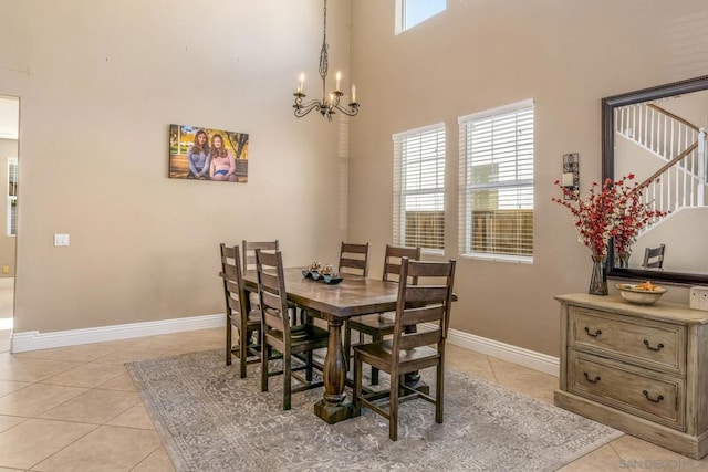 dining room with a towering ceiling, light tile patterned flooring, and an inviting chandelier