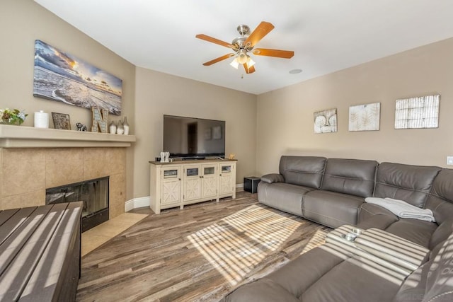 living room with ceiling fan, hardwood / wood-style floors, and a tiled fireplace