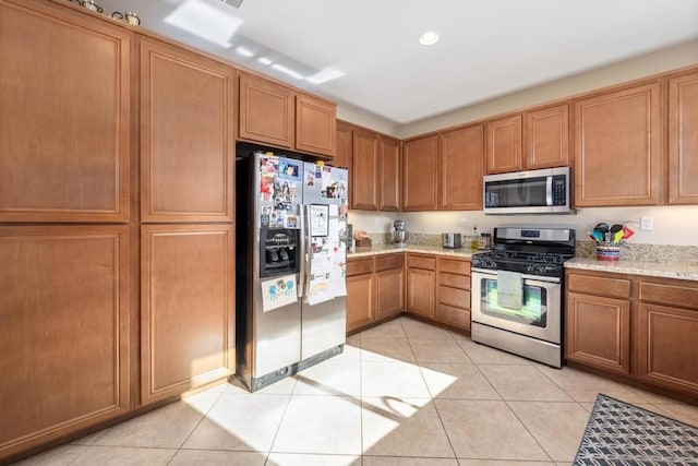 kitchen with light stone counters, light tile patterned floors, and stainless steel appliances